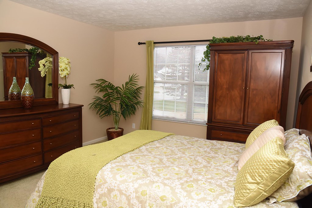 a bedroom with a bed and a dresser and a window