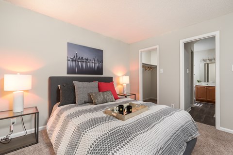 A bedroom with a bed, nightstand, and a painting on the wall.