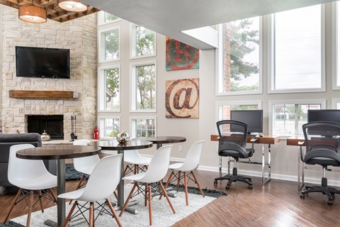 A modern dining room with a stone fireplace and a television above it.