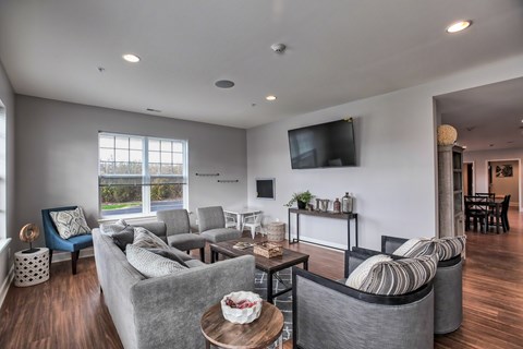 A living room with grey couches and a flat screen TV mounted on the wall.