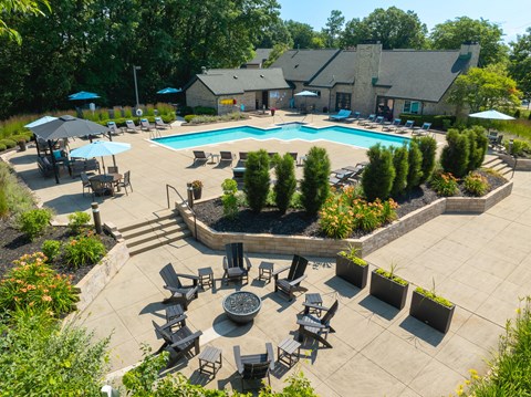 A large outdoor swimming pool surrounded by a patio with chairs and umbrellas.