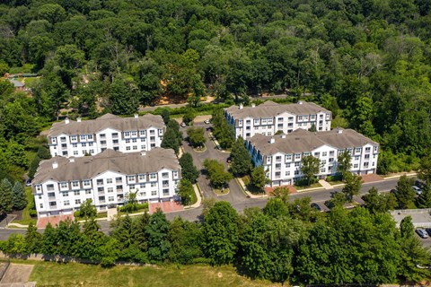 an aerial view of several large white buildings surrounded by trees