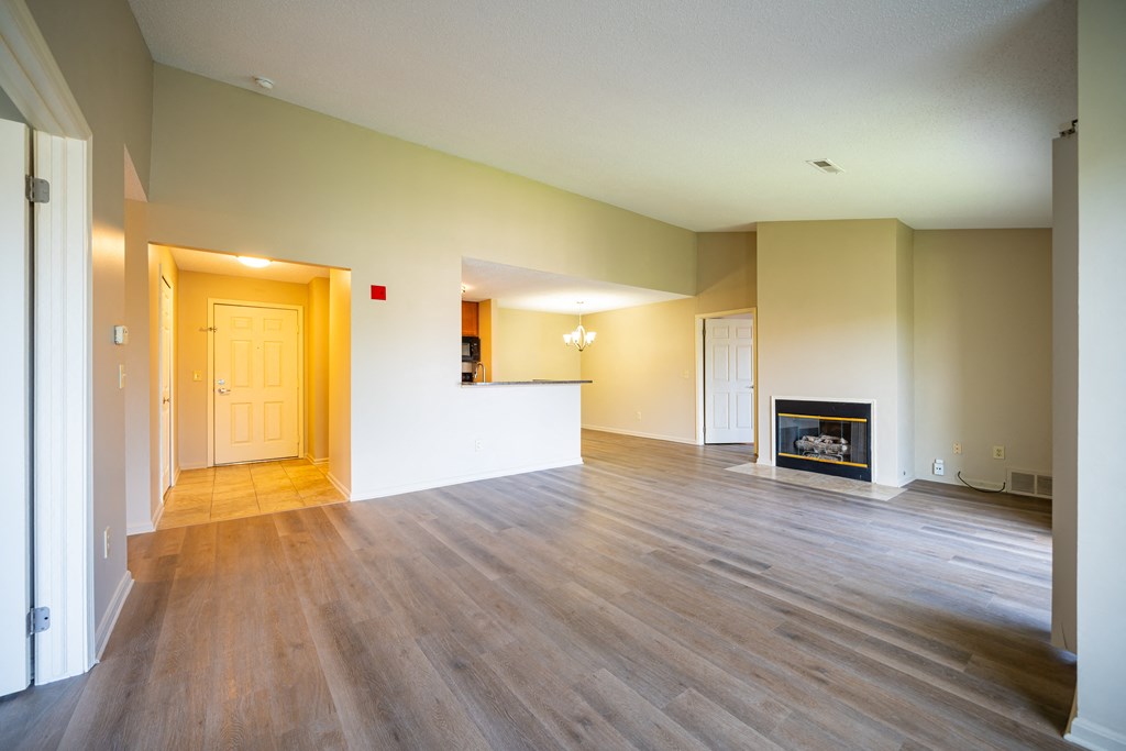 Living room with fireplace and plank floor, kitchen to left