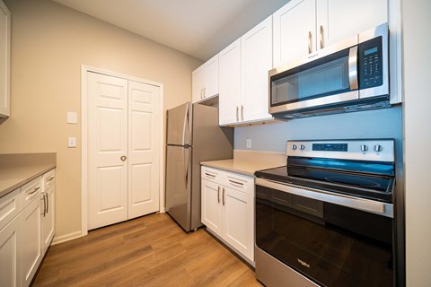 A kitchen with white cabinets and appliances.