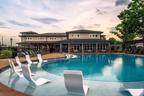 a swimming pool with chairs and a building in the background