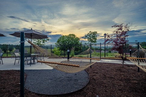 a playground with hammocks and tables and chairs at sunset