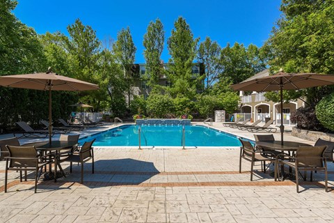 a swimming pool with tables and chairs and umbrellas