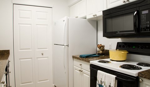 A white refrigerator and a black microwave are in a kitchen.