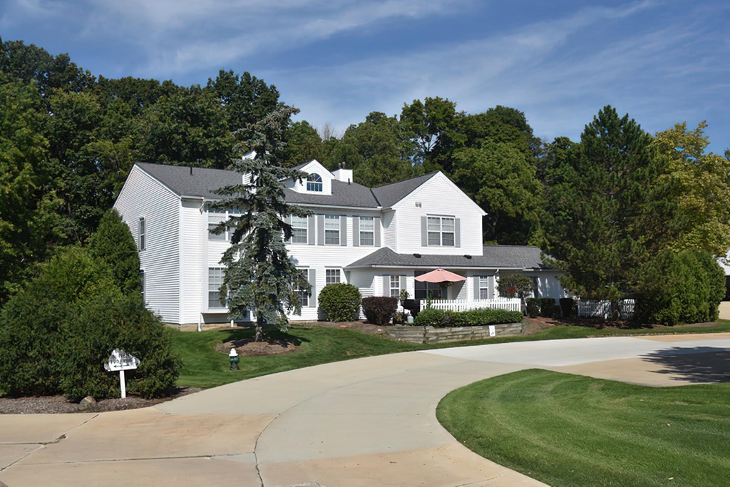 a large white house with a driveway and trees