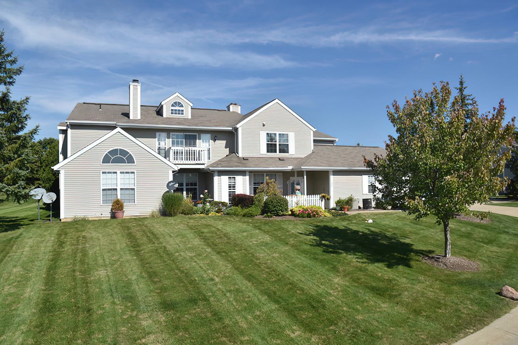 a white house with a lawn and a tree
