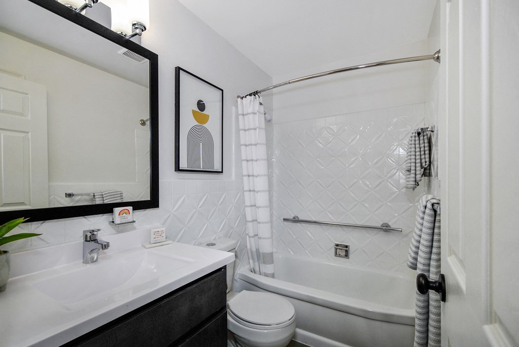 A white bathroom with a black and white tiled shower.
