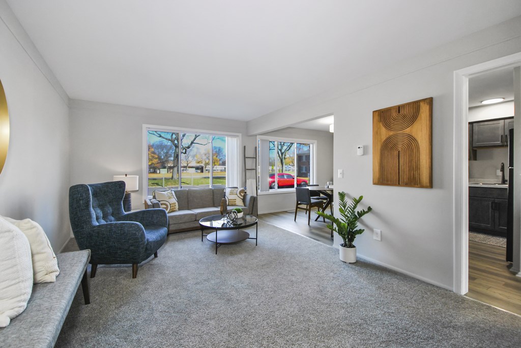 A living room with a grey carpet and a grey sofa.