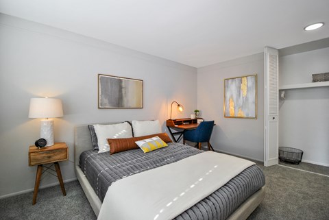 A bedroom with a large bed and a desk with a chair.
