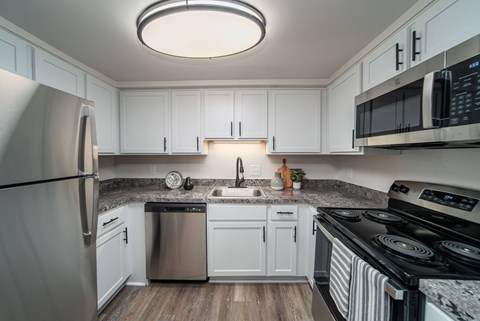 A modern kitchen with white cabinets and stainless steel appliances.