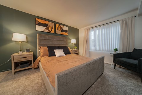 A bedroom with a large bed and a nightstand with a lamp.