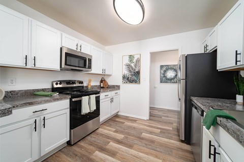 A kitchen with white cabinets and a black fridge.