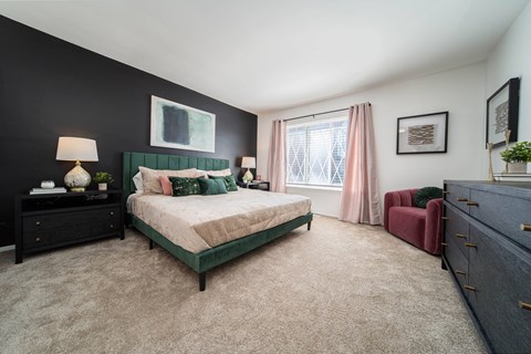 A bedroom with a green bed and a red chair.
