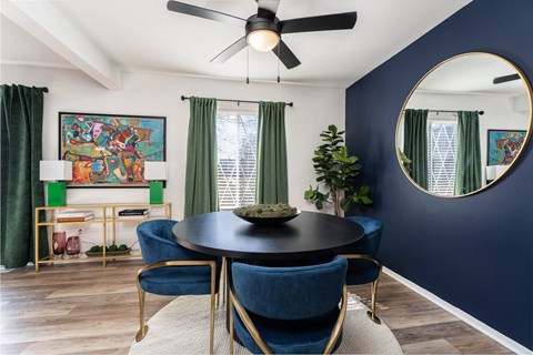 A dining room with a round table and blue chairs.