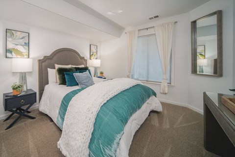 A bedroom with a large bed and a mirror on the wall.