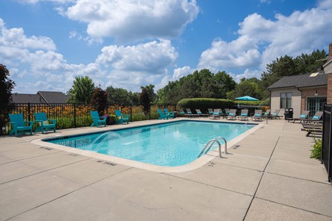 A swimming pool surrounded by blue chairs and a fence.