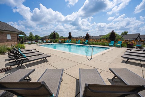 A pool surrounded by wooden benches on a sunny day.