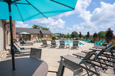 A sunny day at the poolside with blue umbrellas and lounge chairs.