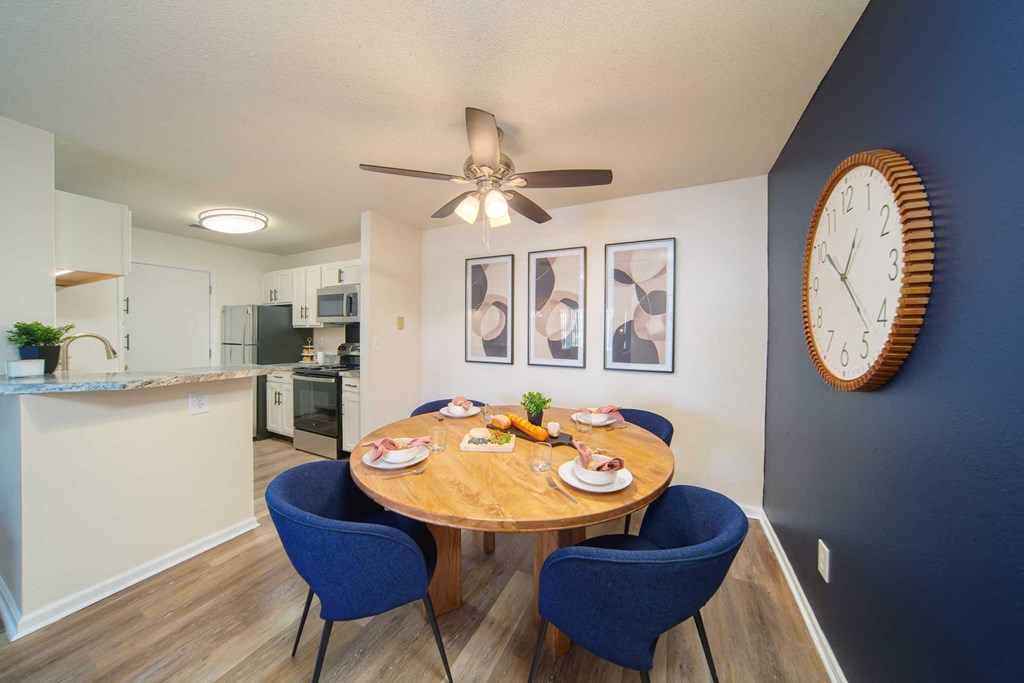 a dining room table with chairs and a clock on the wall