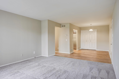 an empty living room with a hard wood floor and a door to a bedroom