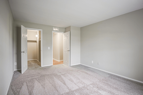 an empty living room with carpet and a door to a hallway