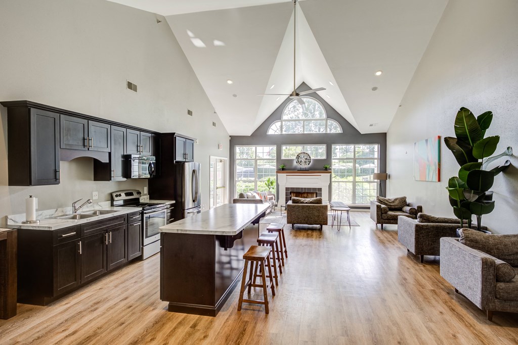 the kitchen and living room of a house with a vaulted ceiling and large windows