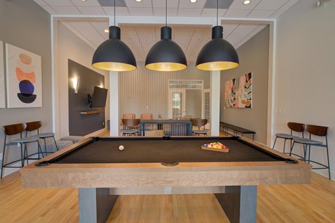 a pool table in a game room with three lamps hanging over it