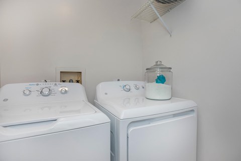 Two white front loading washing machines in a laundry room.