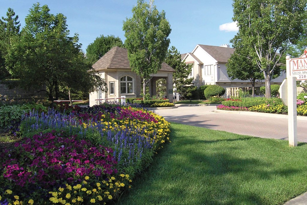 a yard with flowers and a sign in front of a house