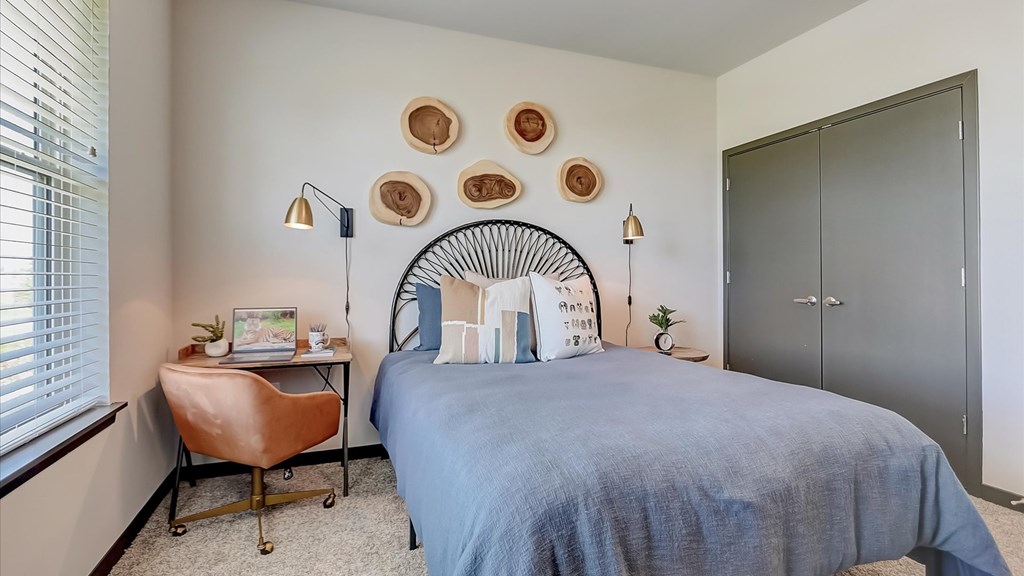 A bedroom with a bed, a chair, and a desk.