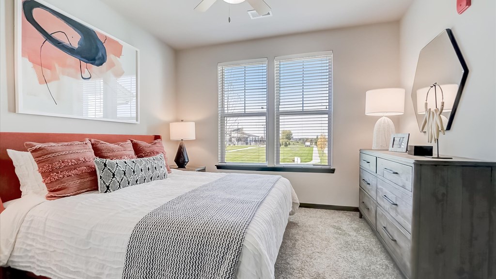 A bedroom with a large bed, a window with blinds, and a ceiling fan.