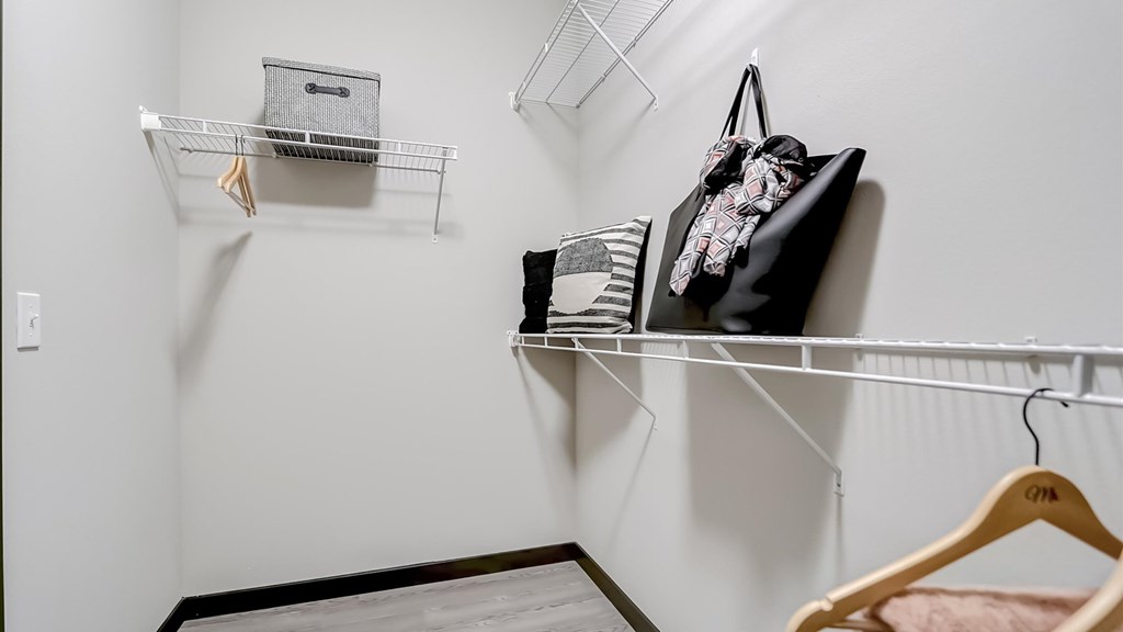 A room with a white wall and a black bag hanging on a shelf.