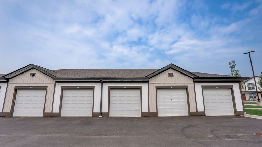 A building with four garage doors is under a blue sky.