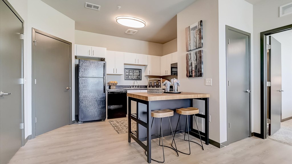 A kitchen with a bar stool and a fridge.