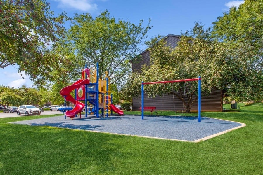A playground with a red slide and a blue swing set.