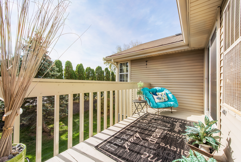 a patio with a chair and a rug on a porch