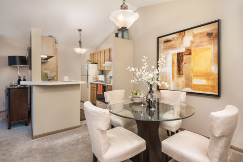 a dining room with a glass table and chairs and a kitchen