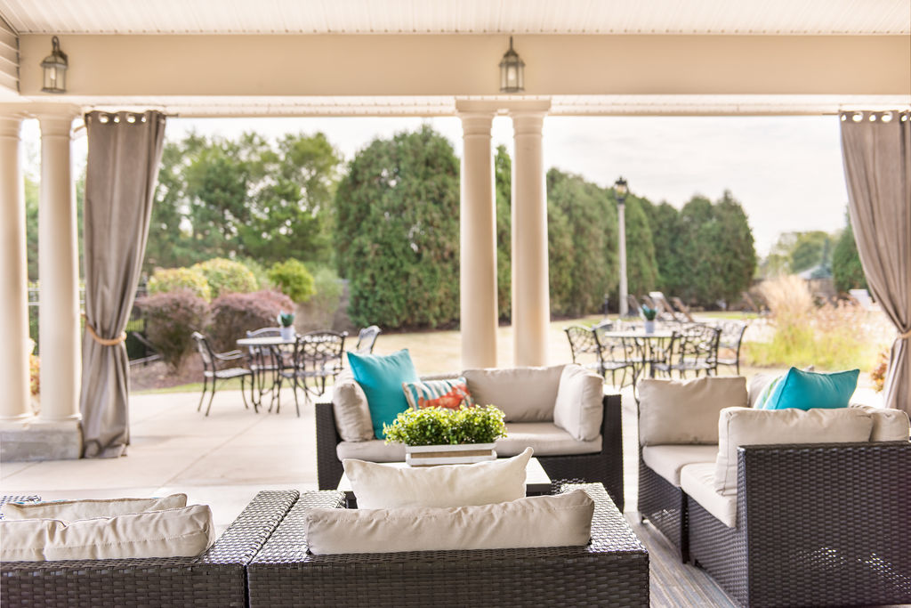 a covered patio with wicker furniture and a table with chairs