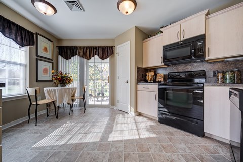 A kitchen with a table and chairs in front of a window.