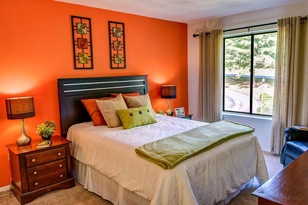 a bedroom with an orange accent wall and a bed