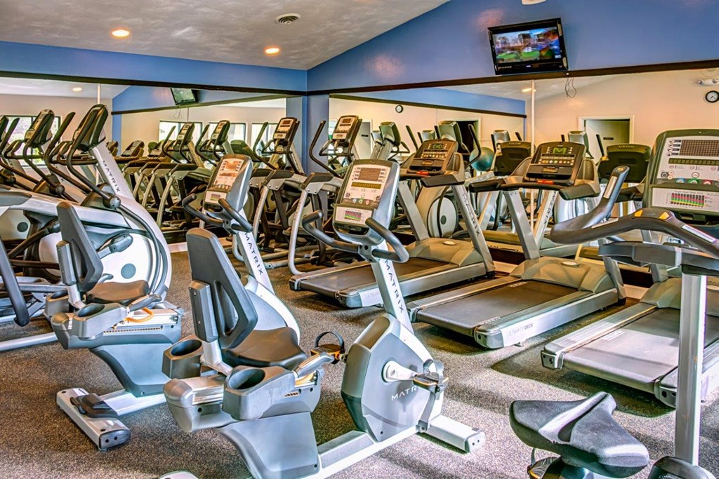 a gym with cardio equipment and a flat screen tv