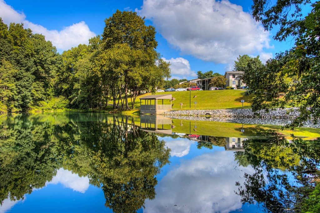 a view of a pond with a house and trees reflected in it