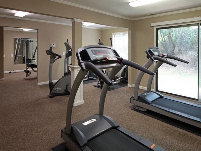 a gym with cardio equipment and a large window