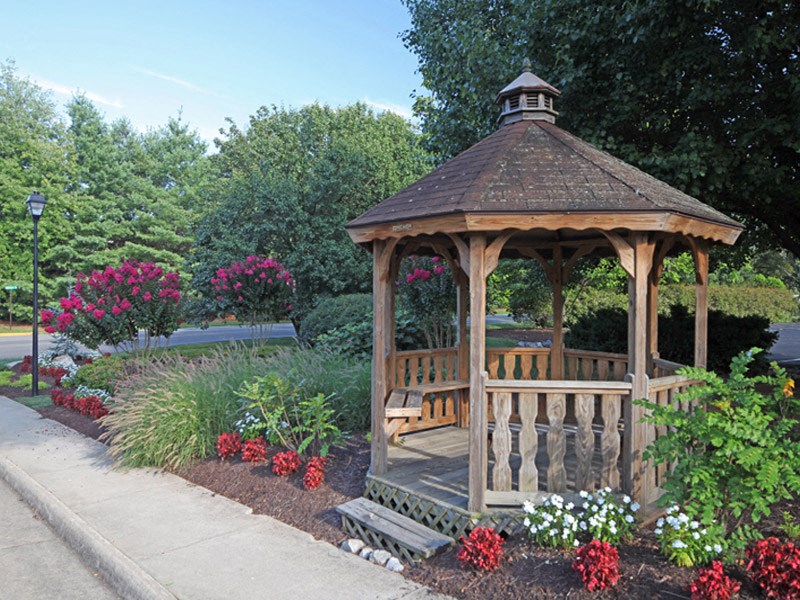 a gazebo with a bench in a garden