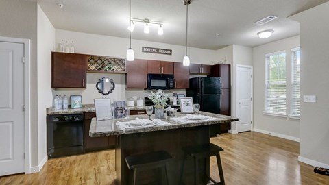 A kitchen with a brown countertop and a black chair.