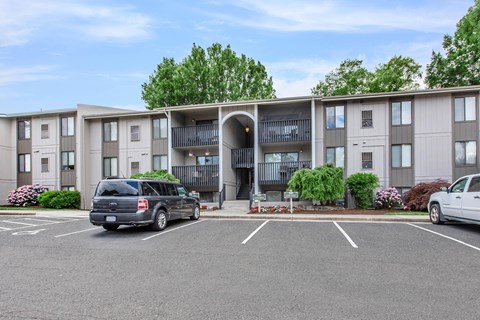 an exterior view of an apartment building with cars parked in a parking lot